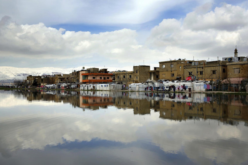 Syrian refugee's tents are reflected in a pool of rain water at a refugee camp in the town of Bar Elias, in the Bekaa Valley, Lebanon. (AP)