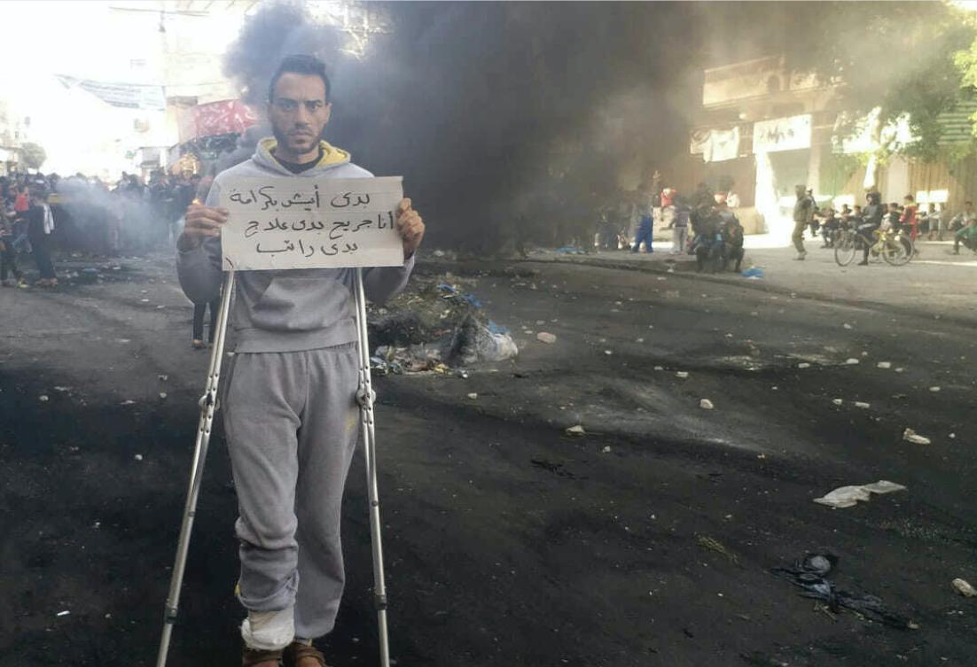 This photo provided by Palestinian journalist Osama al-Kahlout shows a protestor holding a sign that reads in Arabic,