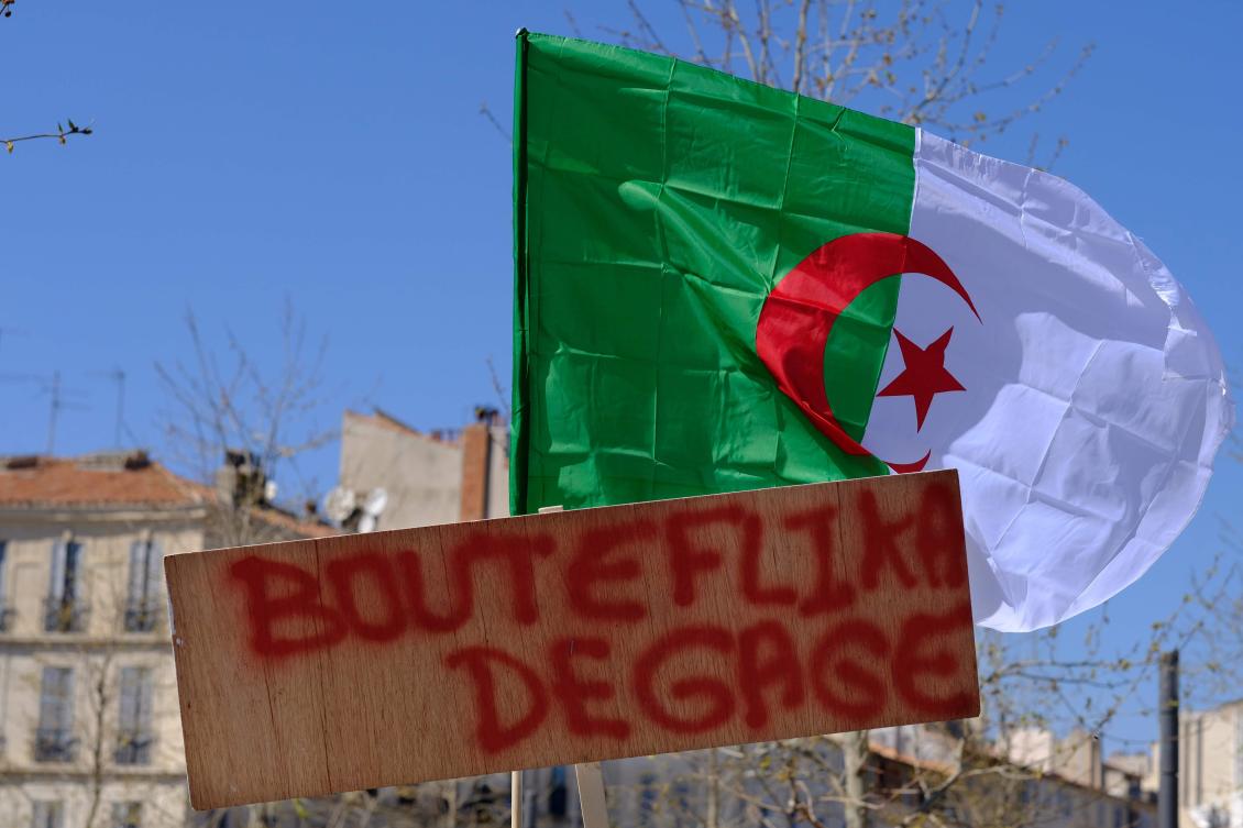 An Algerian flag is seen behind a placard reading