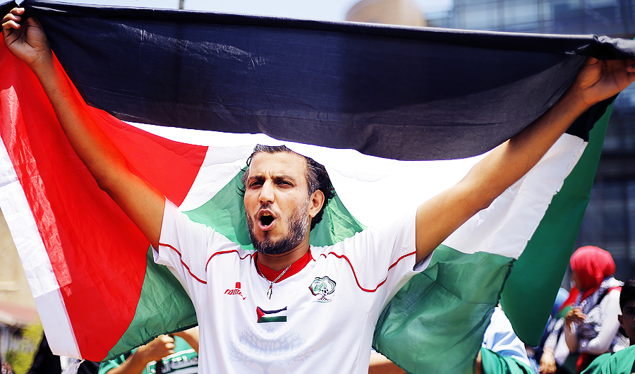A Palestinian holds up a Palestine flag as he chants slogans during a demonstration organized by the Islamic militant group Hamas against a U.S.-sponsored Middle East economic workshop in Bahrain. (AP)