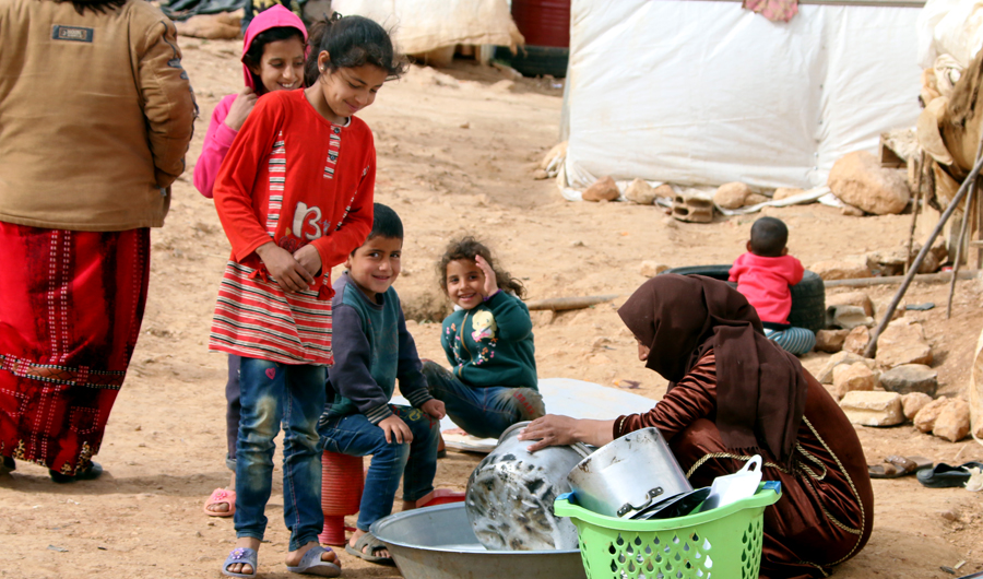A Syrian woman washes the dishes at an unofficial refugee camp in Lebanon's Bekaa valley. (AFP/File)