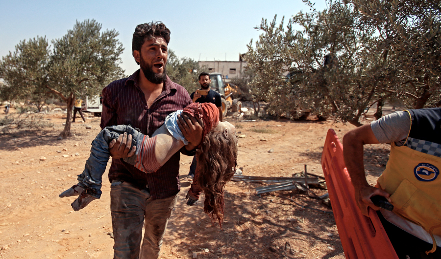 A Syrian carries the body of a child at the site of a regime airstrike on the village of Deir Sharqi in Maaret Al-Numan, Idlib on Saturday. (AFP)
