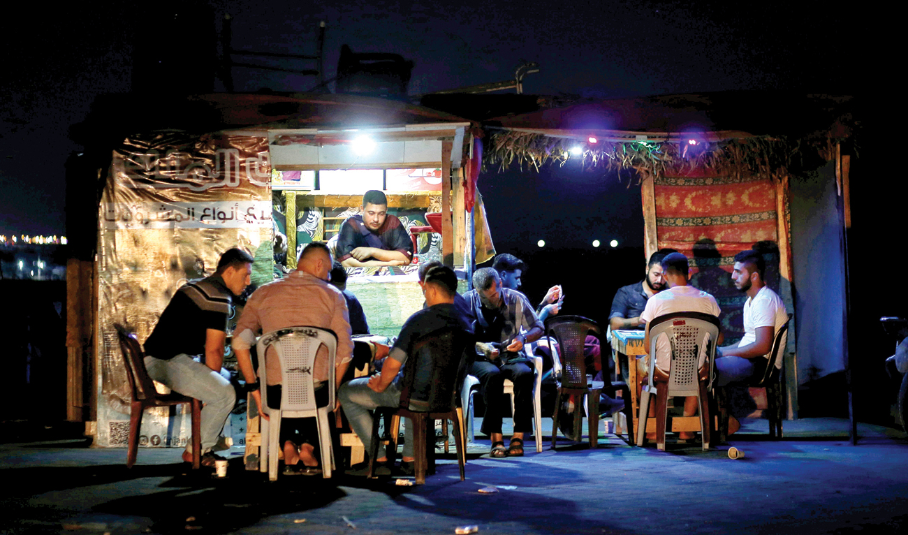 Palestinians play cards during power cut at a roadside coffee shop lit by battery-powered lights in the northern Gaza Strip. (Reuters)