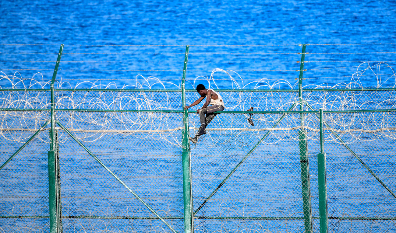 A migrant forces his way into the Spanish territory of Ceuta on August 30, 2019 . Over 150 migrants made their way into Ceuta after storming a barbed-wire border fence with Morocco. (AFP)