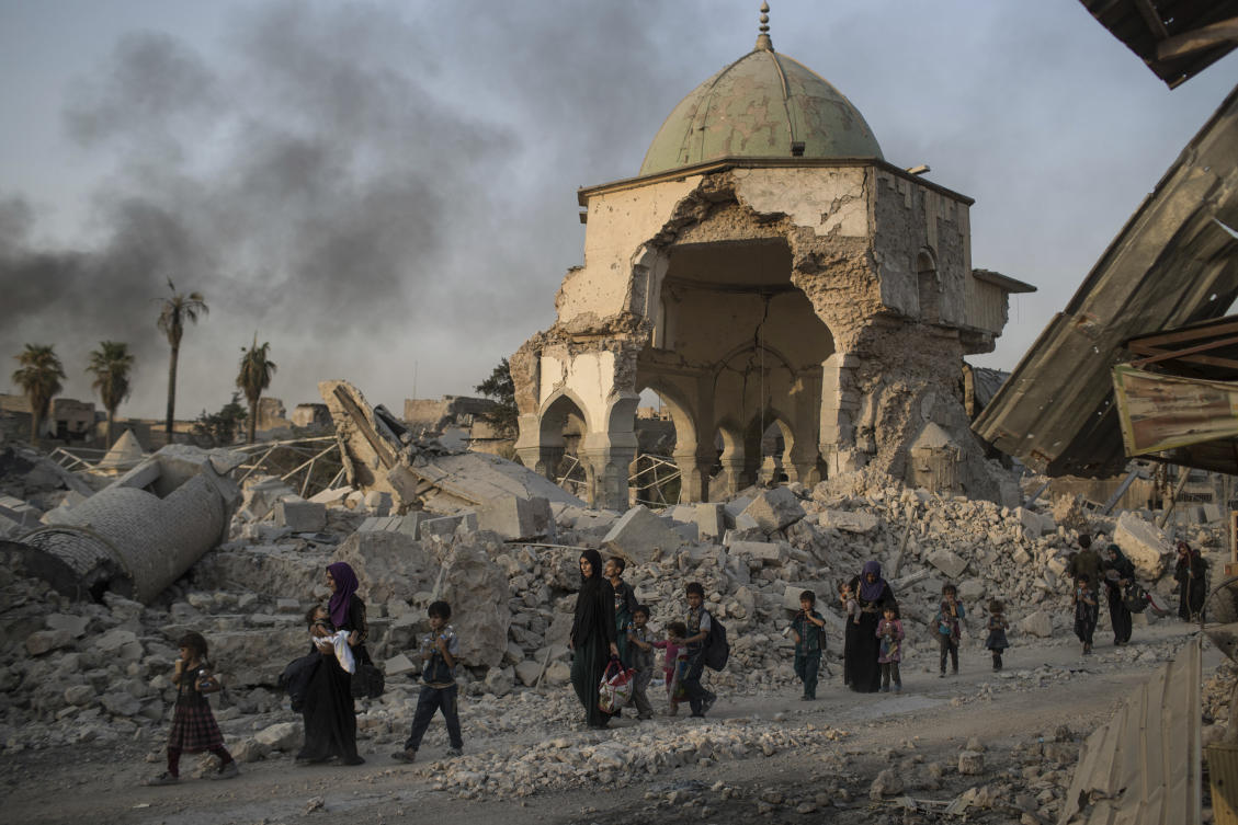 In this July 4, 2017, file photo, fleeing Iraqi civilians walk past the heavily damaged al-Nuri mosque as Iraqi forces continue their advance against Daesh militants in Iraq's Old City of Mosul. The United Nations' cultural agency says reconstruction of Al-Nouri Mosque in Iraq's city of Mosul is scheduled to start at the beginning of 2020. (AP)