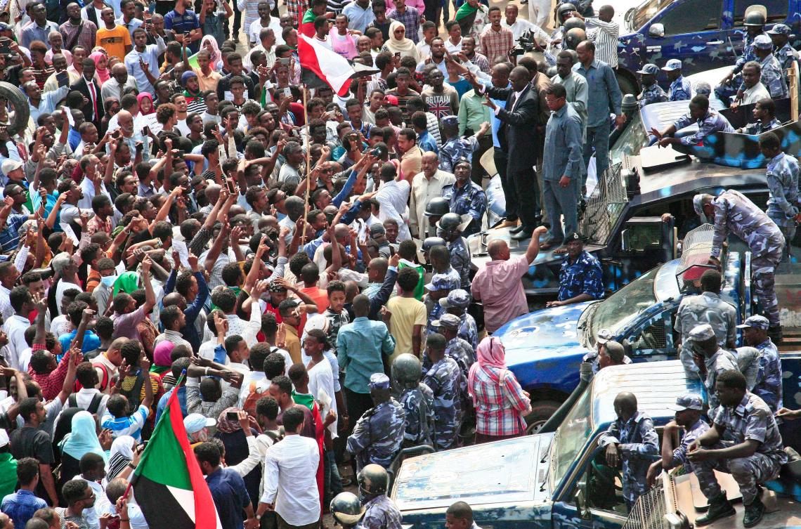 A Sudanese demonstrator waves his hands as he stands on the hood of a security forces' vehicle, urging others not to cross the security barrier, during a protest near the presidential palace in Sudan's capital Khartoum on September 12, 2019, calling for the appointment of a new permanent chief of judiciary and prosecutor general. (AFP)