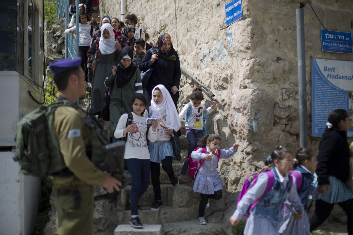 In this March 21, 2019 file photo, an Israeli solider stands guard as Palestinian school children cross back from school in the Israeli controlled part of the West Bank city of Hebron. (AP)