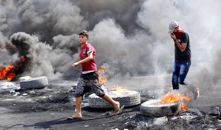 Demonstrators are seen as tires burn during a curfew, two days after the nationwide anti-government protests turned violent, in Baghdad on Thursday. (Reuters)