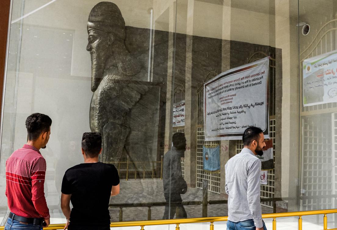 Men look at a replica of a "lamassu", an Assyrian protective deity depicted with a human head, the body of a lion, and bird wings, on the day of its unveiling at the University of Mosul in the northern Iraqi city on October 24, 2019. (AFP)