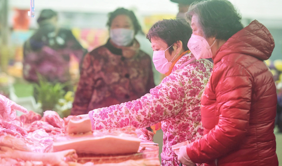 This photo taken on February 9, 2020 shows people wearing protective masks buying meat in Hangzhou in China's eastern Zhejiang province. (AFP)