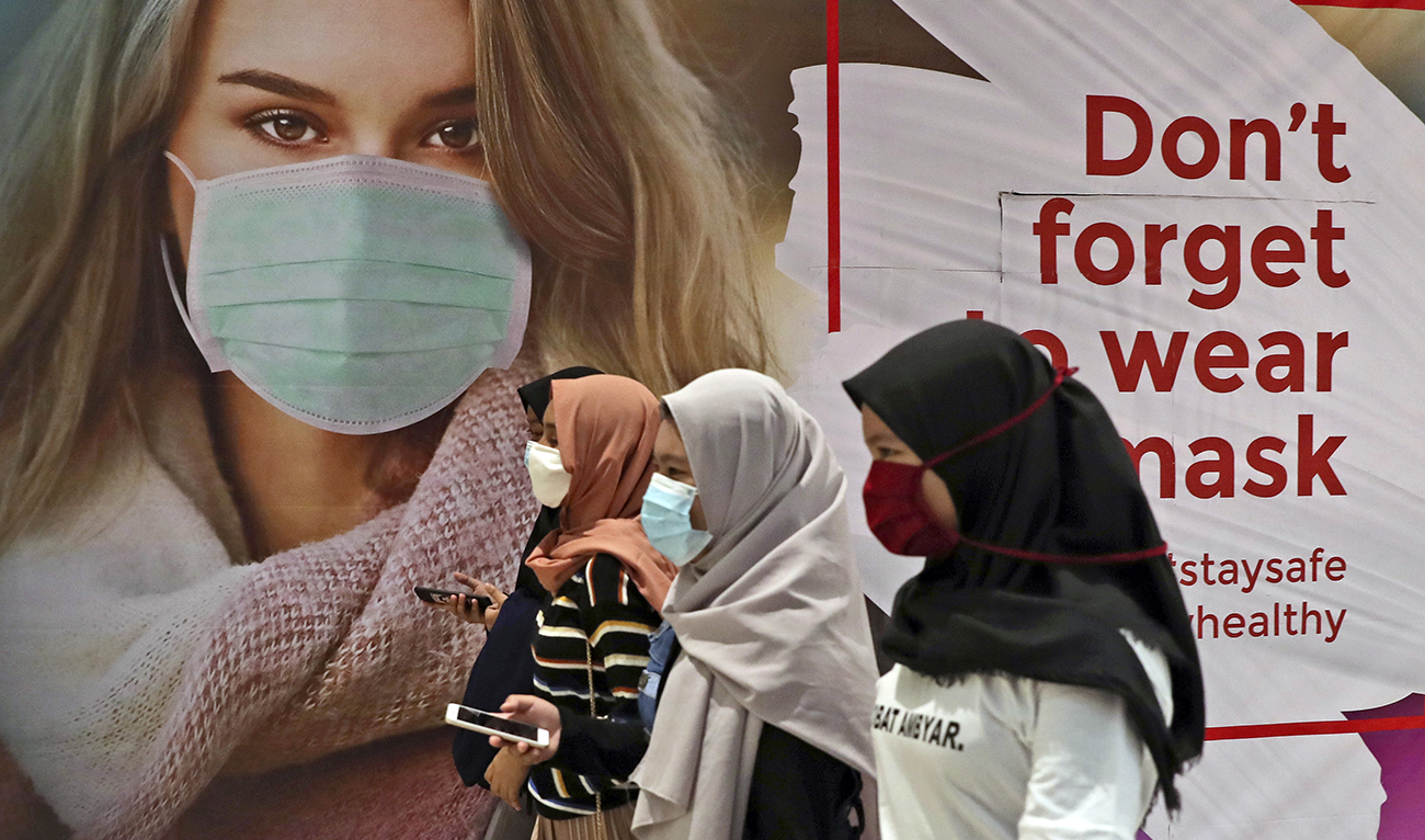 Women wearing protective face masks pass an advertisement promoting awareness of the coronavirus outbreak at a shopping mall in Jakarta, Indonesia, Wednesday, July 1, 2020. (AP)