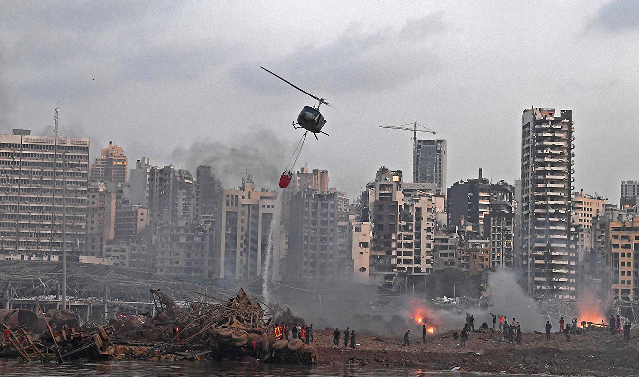 A helicopter tries to put out multiple fires at the scene of the massive explosion that hit port in Beirut killing more than 100 Lebanese, as rescuers search for survivors on Wednesday. (AFP)