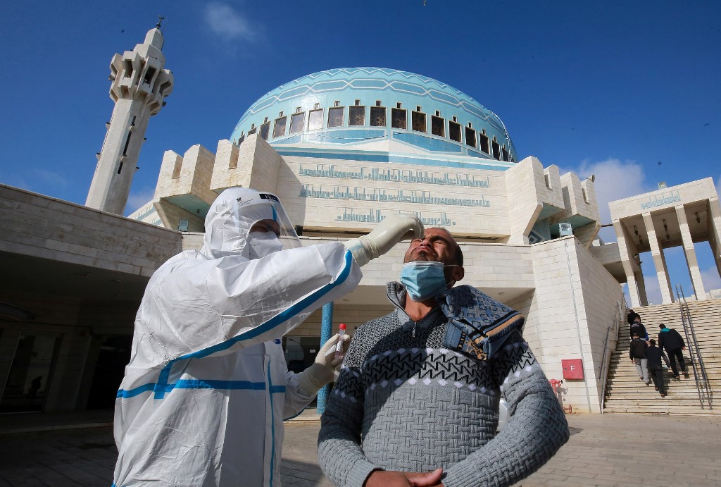 A member of the Jordanian health ministry’s epidemiological investigation team takes a random nasal swab to test for coronavirus, from a man leaving the King Abdullah I mosque following the Friday noon prayers, in the capital Amman, on Dec. 18, 2020. (AFP)