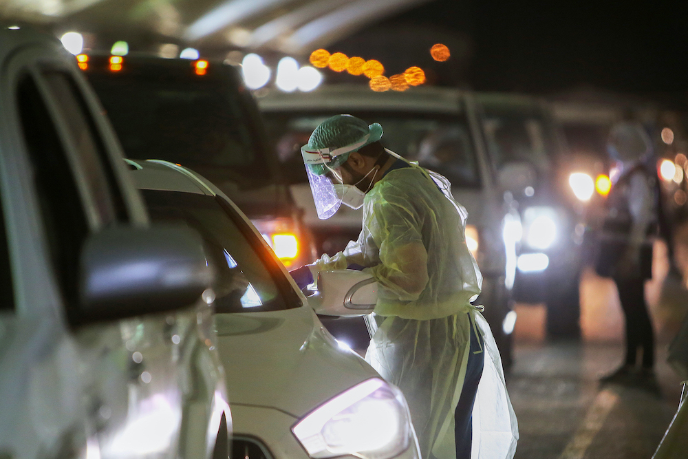 A Kuwaiti health worker conducts PCR test at a COVID-19 drive-thru testing center near Kuwait International Airport in Kuwait City. (File/AFP)