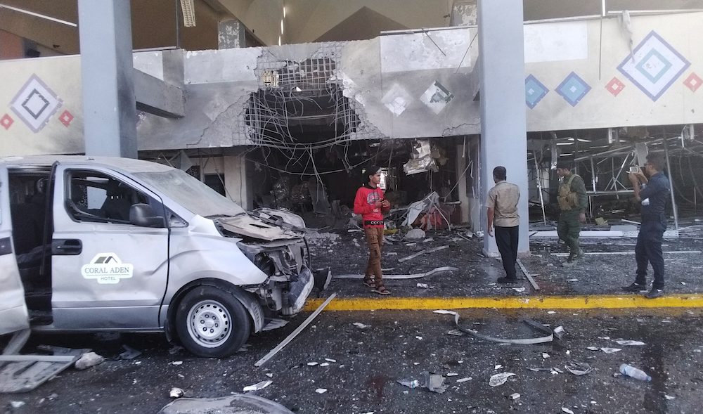 Bystanders and a soldier stand near a damaged portion of the airport of Yemen’s southern city of Aden after an explosion, Wednesday, Dec. 30, 2020. (AP)