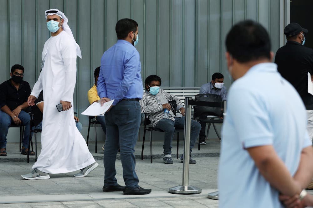 A member of hospital staff, wearing a protective face mask, watches over people queuing to be tested for coronavirus, at the Cleveland Clinic hospital in Abu Dhabi, UAE. (File/Reuters)