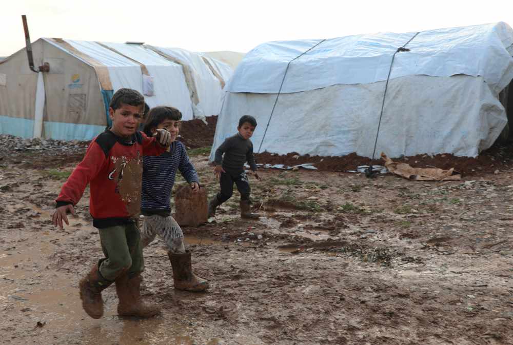 Internally displaced Syrian children walk in a mud near tents, in northern Aleppo countryside, Syria, on January 20, 2021. (REUTERS/Mahmoud Hassano)