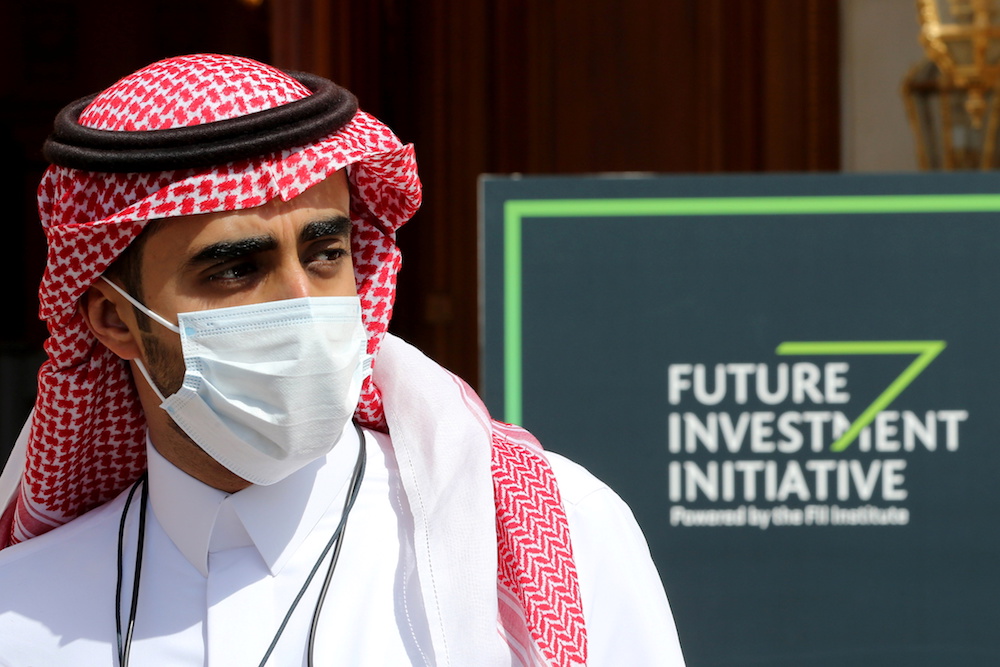 A Saudi man walks past a logo of the Future Investment Initiative ahead of the opening ceremony of the fourth annual conference in Riyadh, Saudi Arabia January 27, 2021. (Reuters)
