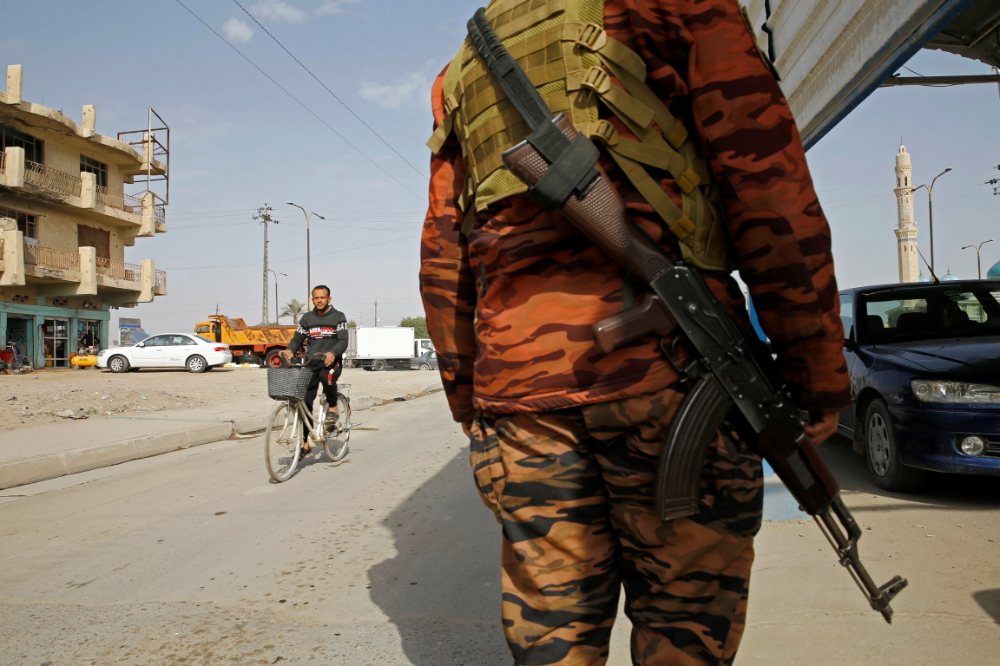 An Iraqi policeman carries a weapon at a checkpoint in Fallujah, Iraq. (Reuters)