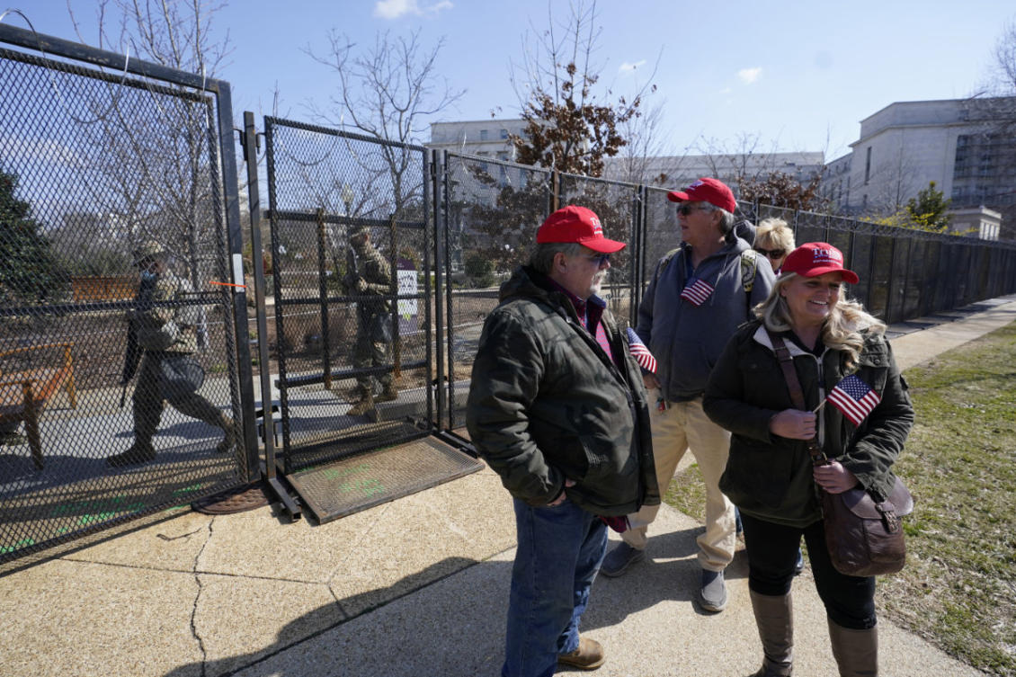 Supporters of former President Donald Trump stand outside of security fencing around the US Capitol in Washington D.C. as members of the national guard walk on the other side  on March 4, 2021. (AP Photo/Alex Brandon)