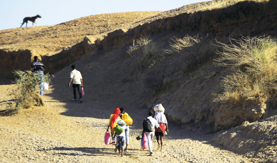 Ethiopians, who fled the ongoing fighting in Tigray region, carry their belongings after crossing the Sudan-Ethiopia border, in Sudan’s Kassala state. (Reuters)