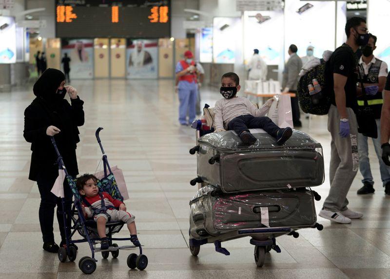 A Kuwaiti family repatriated from Amman, wearing protective face masks, prepare their luggage while arriving at Kuwait Airport, following the outbreak of the coronavirus disease (COVID-19), in Kuwait City, Kuwait April 21, 2020. (Reuters)