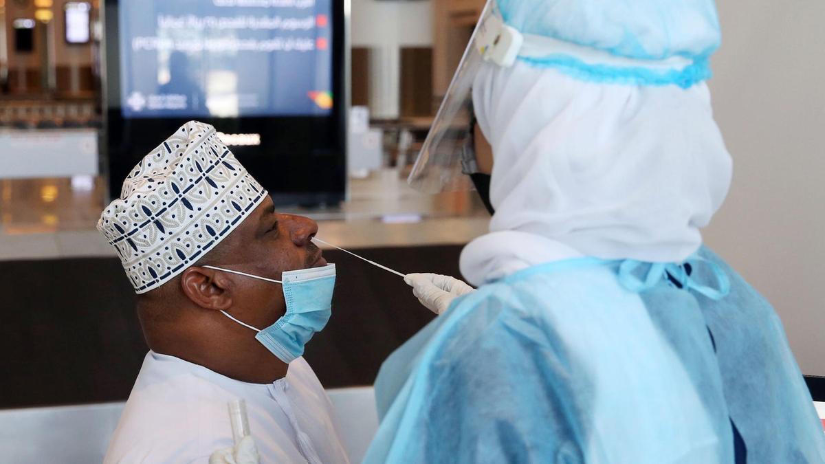 A medical worker collects a swab sample from a passenger for a RT-PCR Coronavirus test at the Muscat international airport in the Omani capital. (File/AFP)