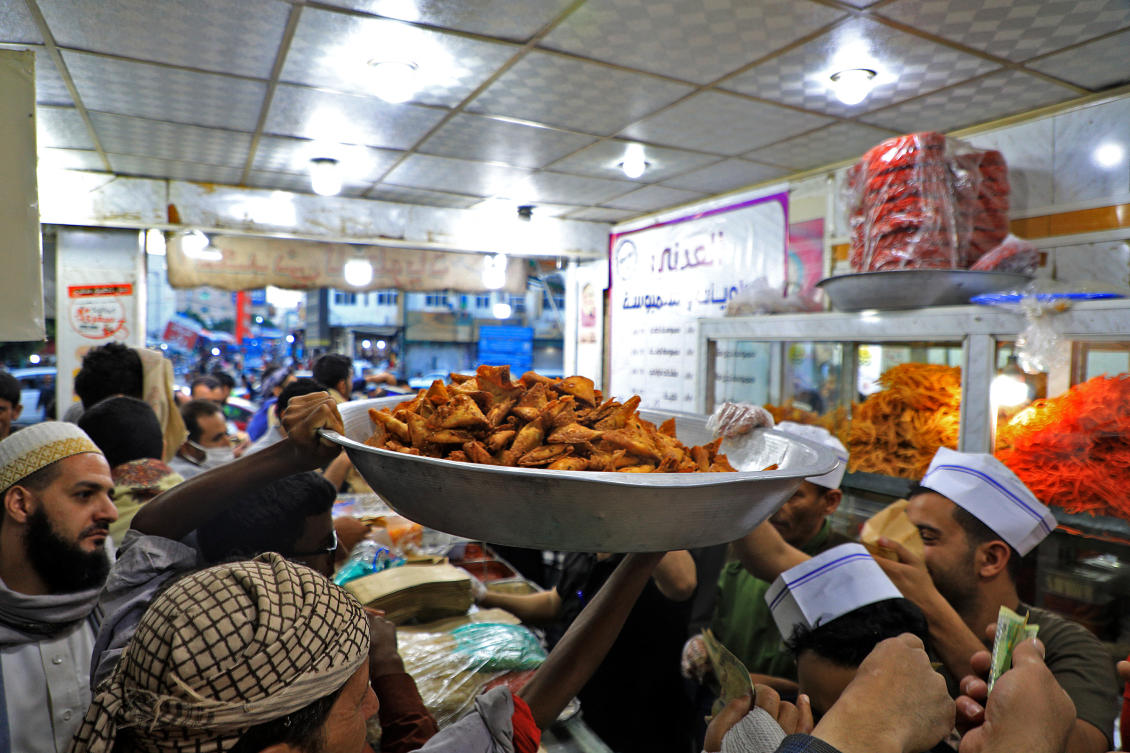 Yemenis queue up in a shop selling “sambusa” in Sanaa late on April 19, 2021 during the Muslim holy month of Ramadan in which practicing Muslims fast from dawn to dusk and eat only after sunset. (File/AFP)