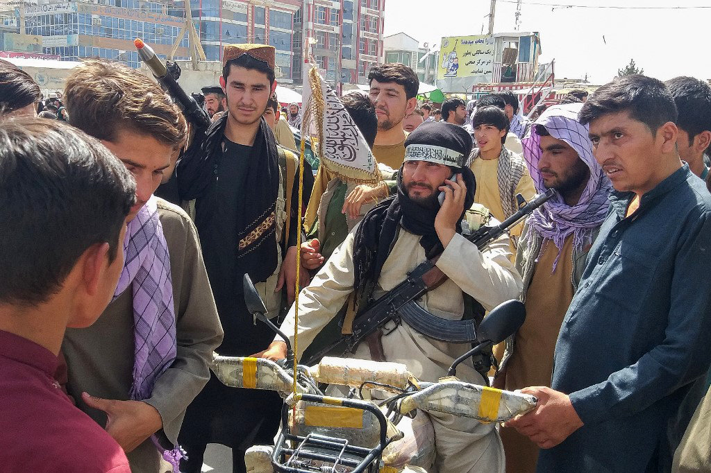 A Taliban fighter is surrounded by locals at Pul-e-Khumri on August 11, 2021 after the group captured Pul-e-Khumri, the capital of Baghlan province about 200 kms north of Kabul. (AFP)