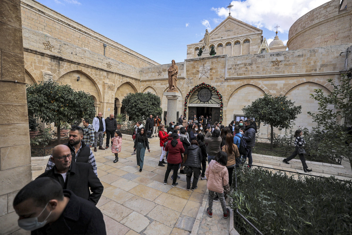 People gather outside the entrance to the Chapel of Saint Catherine at the Church of the Nativity complex on Dec. 19, 2021. (AFP)