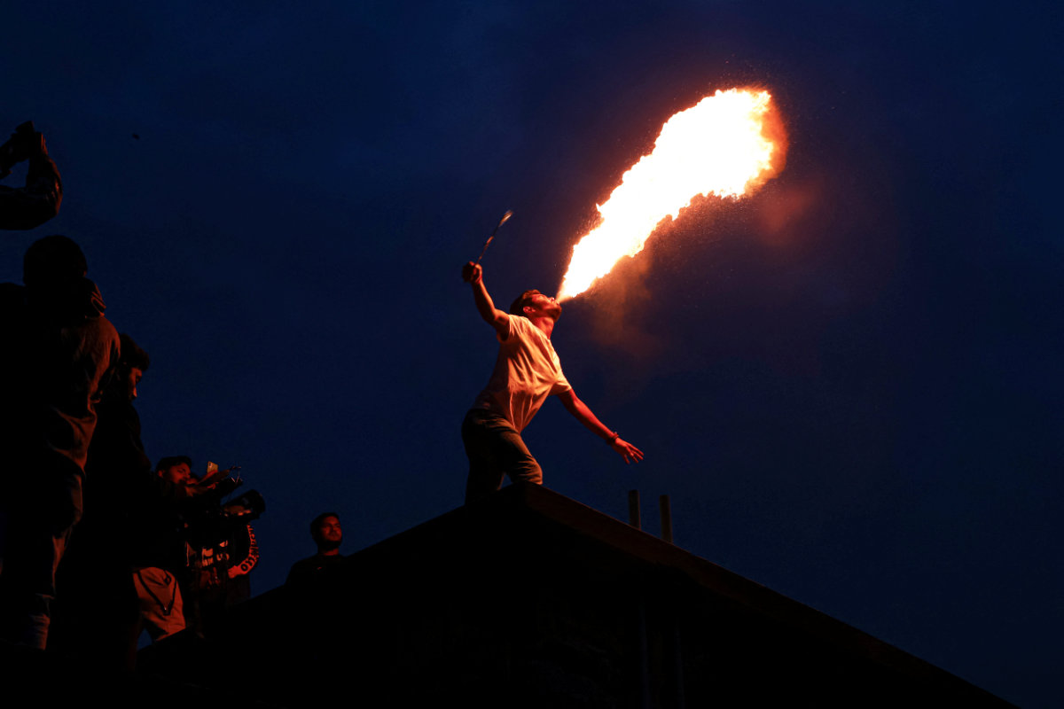 A man performs fire breathing on their rooftop during Shakrain Festival in Dhaka, Bangladesh, on January 14, 2022. (REUTERS/Mohammad Ponir Hossain)