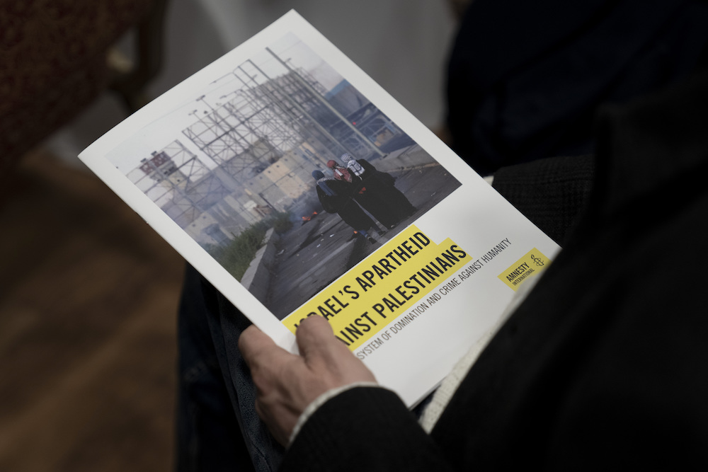 A journalist holds a copy of Amnesty International’s report “Israel’s Apartheid Against Palestinians,” at a press conference on its release in Jerusalem, Tuesday, Feb. 1, 2022. (AP)