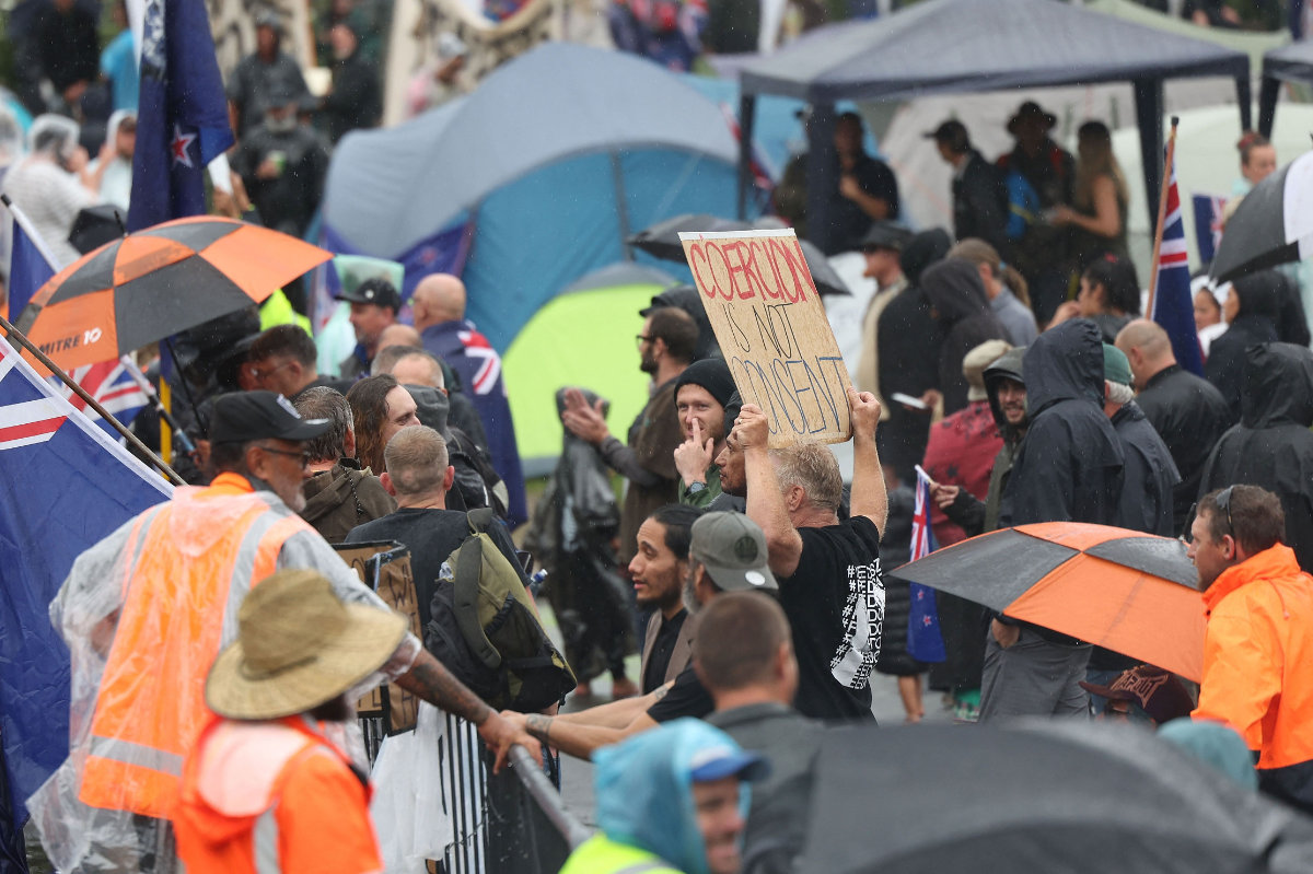 Protesters stand in the rain in Parliament grounds in Wellington on Feb. 12, 2022, during demonstrations against pandemic restrictions, inspired by a similar demonstration in Canada. (AFP) 