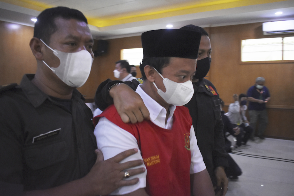 Herry Wirawan, center, the principal of a girls Islamic boarding school accused of raping his students, with security officers during a sentencing hearing at a district court in Bandung, West Java. (AP)
