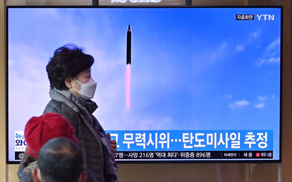 People watch a television screen showing a news broadcast with file footage of a North Korean missile test, at a railway station in Seoul on March 5, 2022. (AFP)
