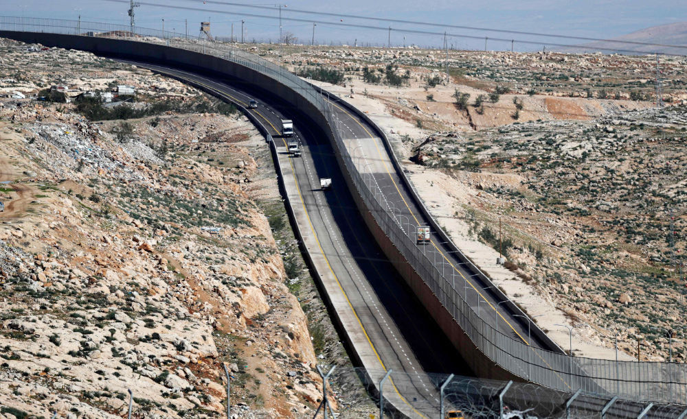 Cars drive on a new Israeli road divided by a wall to separate it for Palestinians (L) and the side to be used exclusively by Israelis and settlers (R) in East Jerusalem, on January 10, 2019. (AFP)