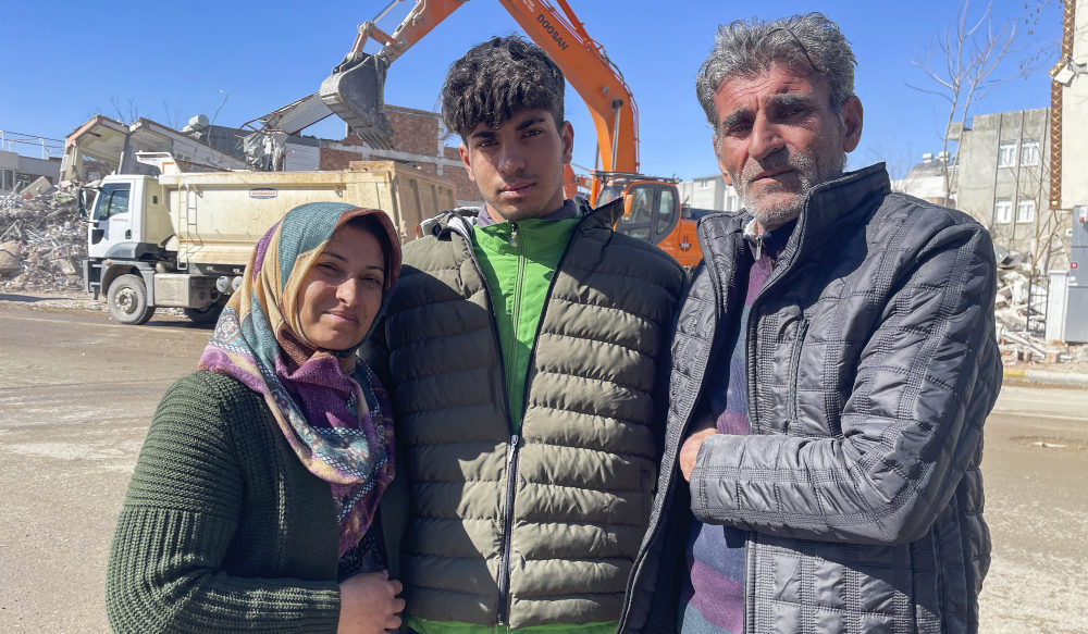 Taha Erdem, 17, center, his mother Zeliha Erdem, left, and father Ali Erdem pose for a photograph next to the destroyed building where Tahan was trapped after the earthquake of Feb. 6, in Adiyaman, Turkey, Friday, Feb. 17, 2023. (AP)