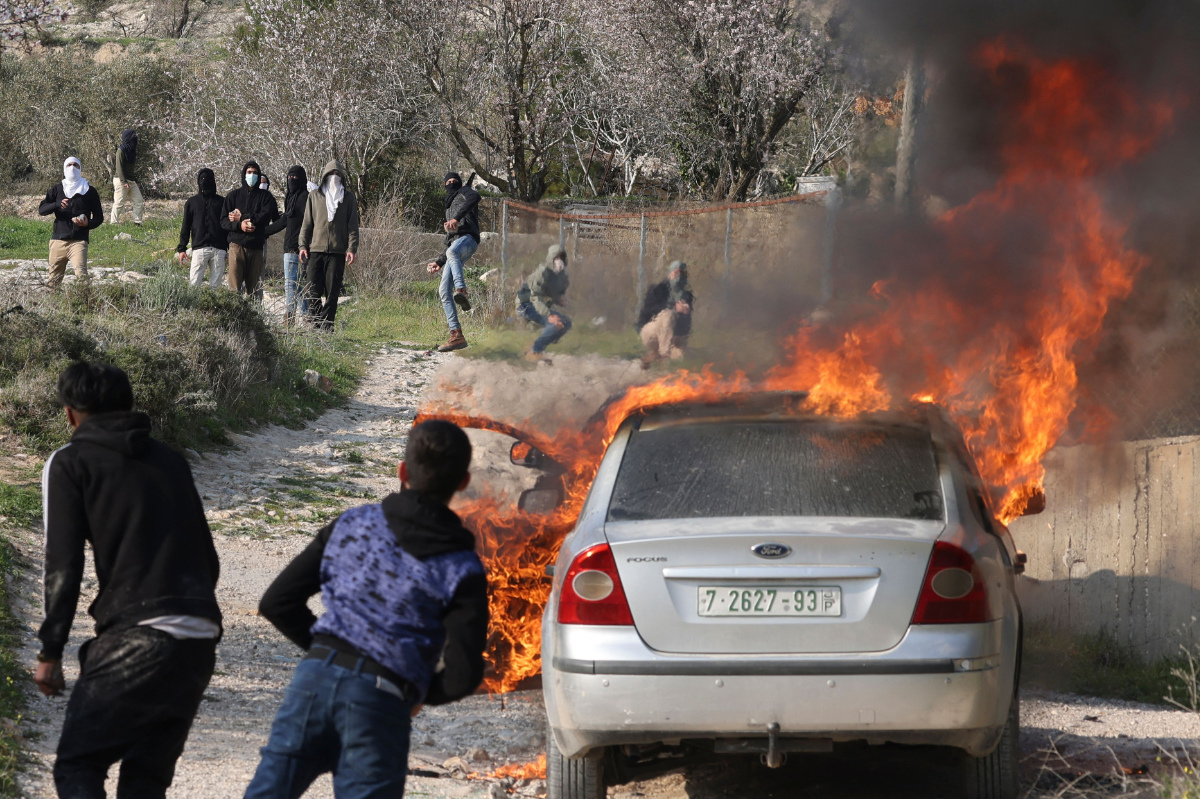 Palestinian youths from Burin village hurl rocks at settlers (background) from the nearby Israeli Bracha settlement who reportedly set fire to cars in the village on Feb. 25, 2023. (AFP)