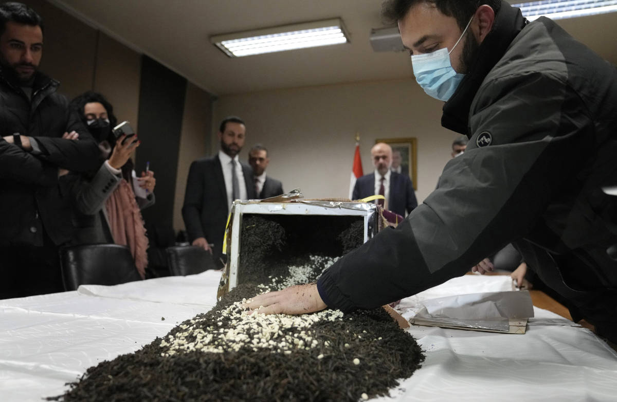 A security officer displays confiscated drugs of Captagon pills which were hidden in 434 exported boxes mixed with seven tons of tea, at the Lebanese police headquarters, in Beirut, Lebanon, Tuesday, Jan. 25, 2022. (AP)