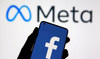 A smartphone with Facebook's logo is seen in front of displayed Facebook's new rebrand logo Meta. (REUTERS)
