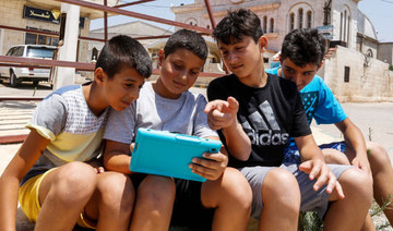 Children look at a cell phone together in the Syrian village of Fairouzah. (AFP)
