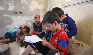 Syrian children study on the ground in abandoned villa