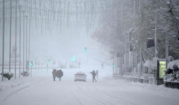 People walk amid a heavy snowfall in Madrid on January 9, 2021. (AFP / GABRIEL BOUYS)