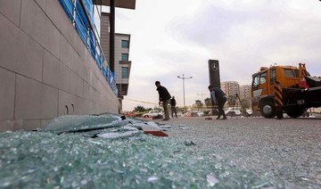A worker cleans shattered glass on Feb. 16, 2021 outside a damaged shop following a rocket attack the previous night in Irbil, the capital of the northern Iraqi Kurdish autonomous region. (AFP)