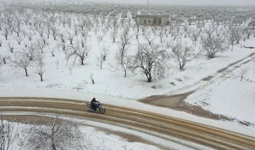 A Syrian man rides a motorcycle among groves covered with snow in the Jabal al-Zawiya region in the rebel-held northern countryside of Syria's Idlib province, on February 17, 2021. (AFP)
