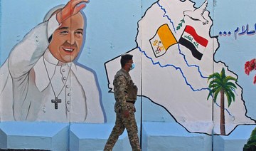 An Iraqi policeman walks past a mural depicting Pope Francis on the outer walls of Our Lady of Salvation (Sayidat al-Najat) Church, in Baghdad on February 22, 2021. (AFP)