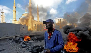 A man stands next to flaming tires at a make-shift roadblock set-up by anti-government demonstrators next to the Mohammed al-Amin Mosque in the Martyrs' Square in the centre of Lebanon's capital Beirut on March 8, 2021. (AFP)