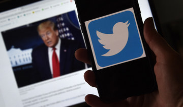 In this photo illustration, a Twitter logo is displayed on a mobile phone with a President Trump's picture shown in the background on May 27, 2020, in Arlington, Virginia. (AFP/File Photo)