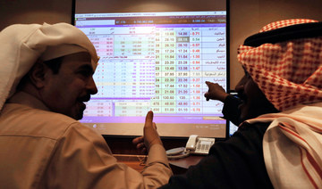Saudi traders chat as they follow a screen displaying Saudi stock market values at the Arab National Bank in Riyadh, Saudi Arabia. (AP file photo)