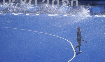 An Australia women's field hockey player walks beneath a sprinkler during a training session ahead of the the 2020 Summer Olympics on July 23, 2021, in Tokyo. (AP Photo/John Locher) 